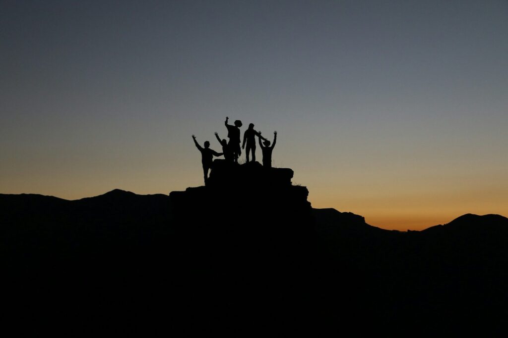 Silhouet van team op bergtop bij gouden zonsondergang - metafoor voor Golden Leadership